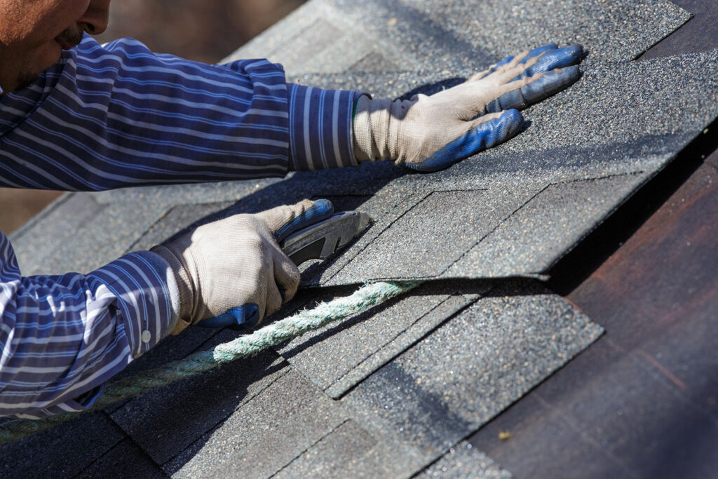 A man fitting shingles to a roof as part of a roofing service - new roof installation